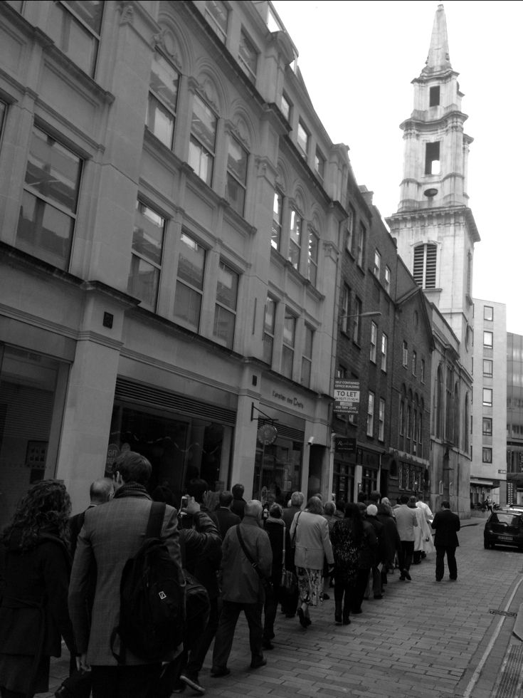 A church procession moving along the street towards St Vedast's tower.