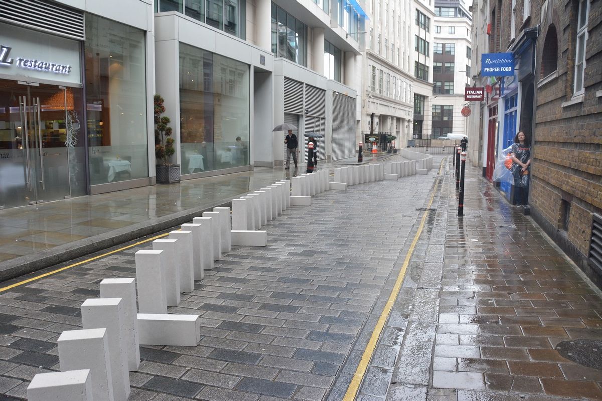 A line of large white blocks stretching along a wet city street.