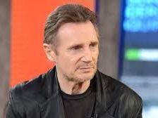 A man in a black jacket seated during an interview.