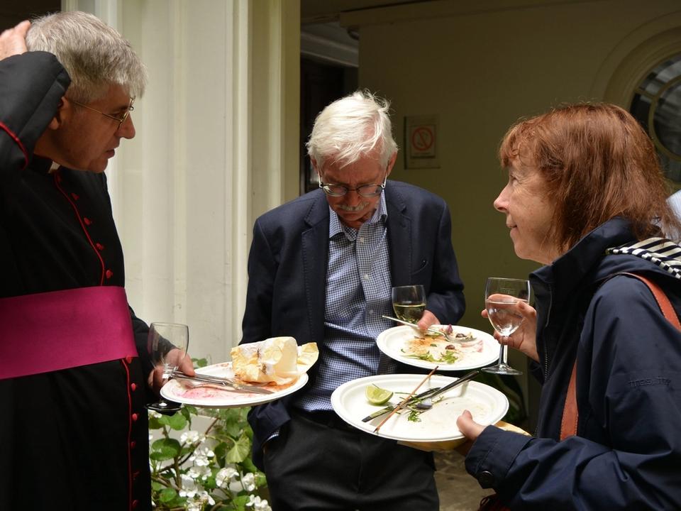 Parishioners eating and talking together in the courtyard.