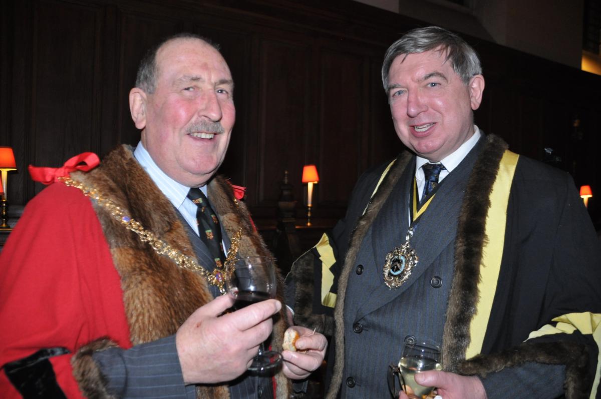 Two guests wearing ceremonial robes and chains at a reception.