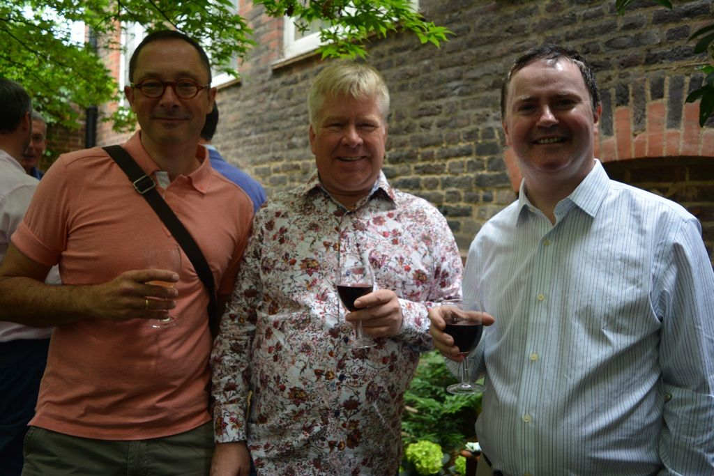 Three guests smiling together in the courtyard.