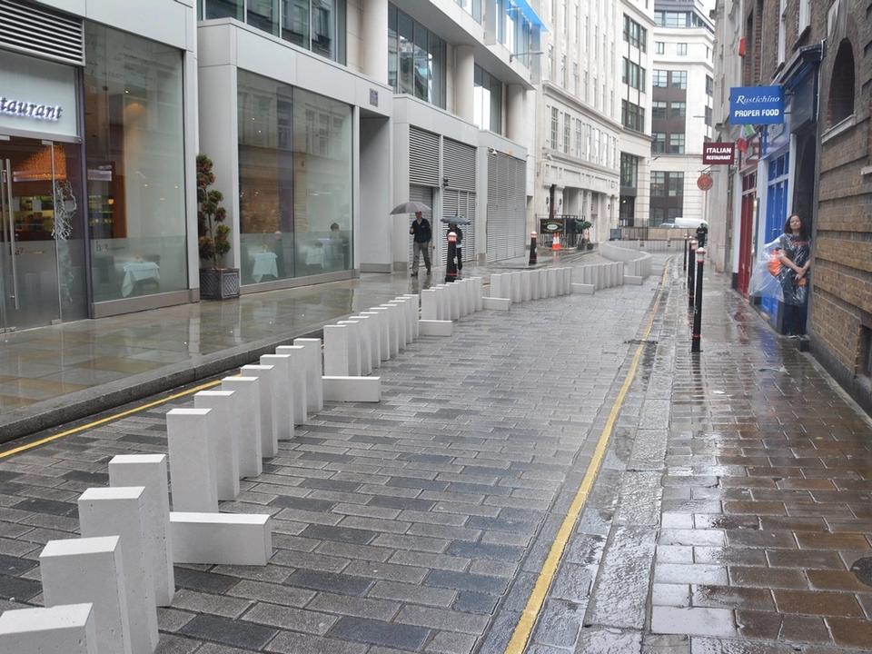 A line of large white blocks stretching along a wet city street.