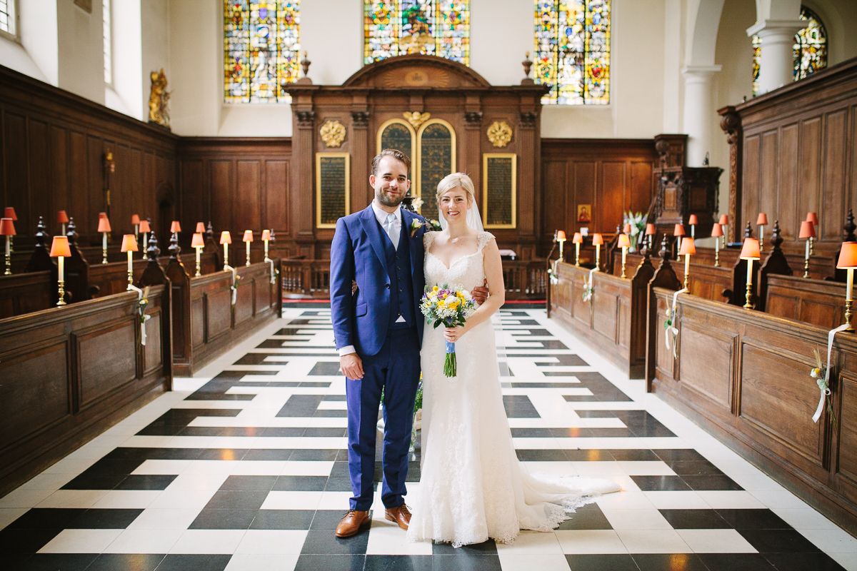A wedding couple standing together in the church's central aisle.