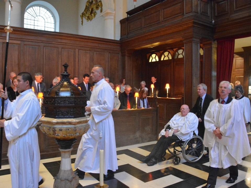 Clergy processing past the font as the congregation stands.