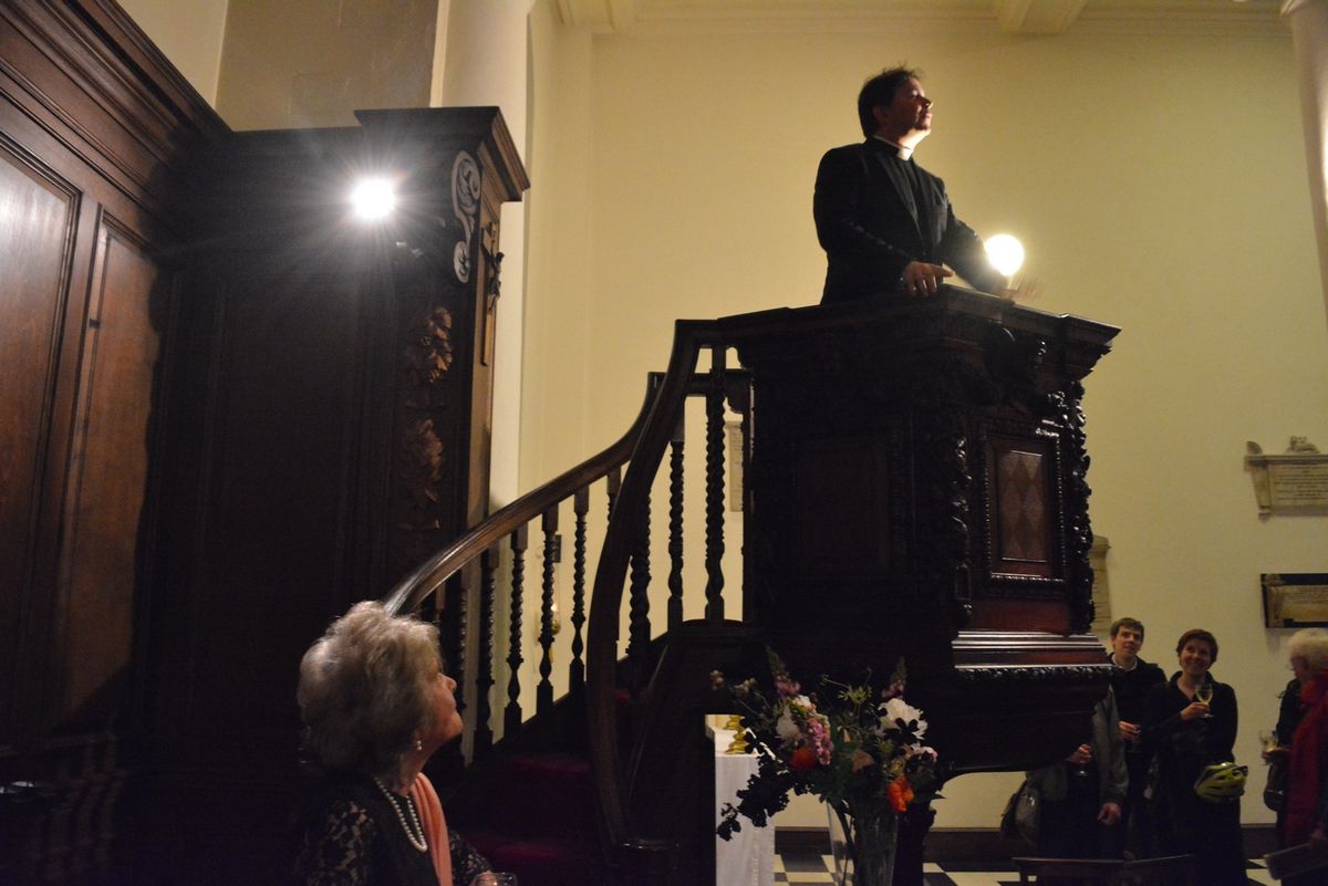 A wide view of a speaker at the pulpit above the congregation.