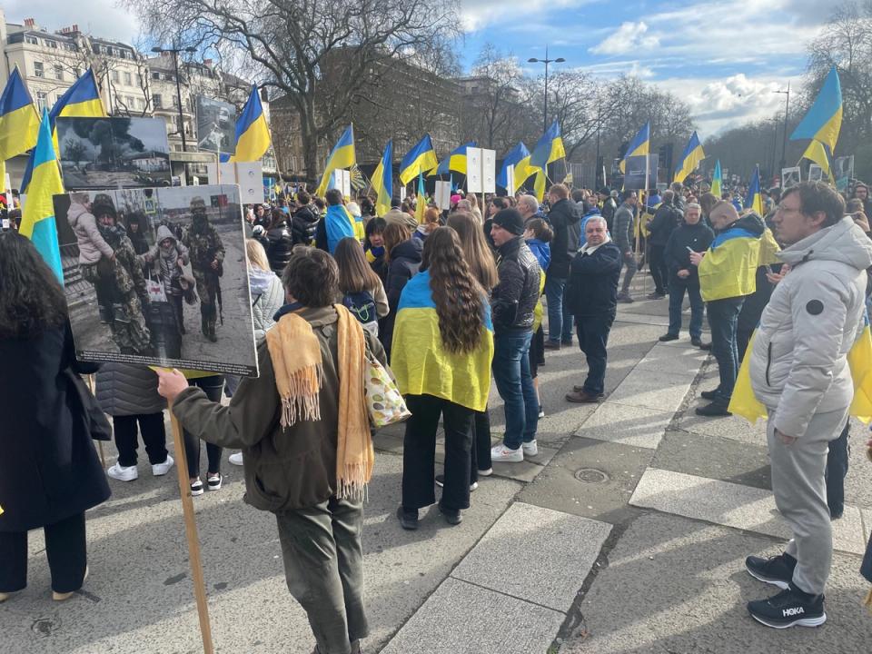 A crowd carrying Ukrainian flags at an outdoor gathering.