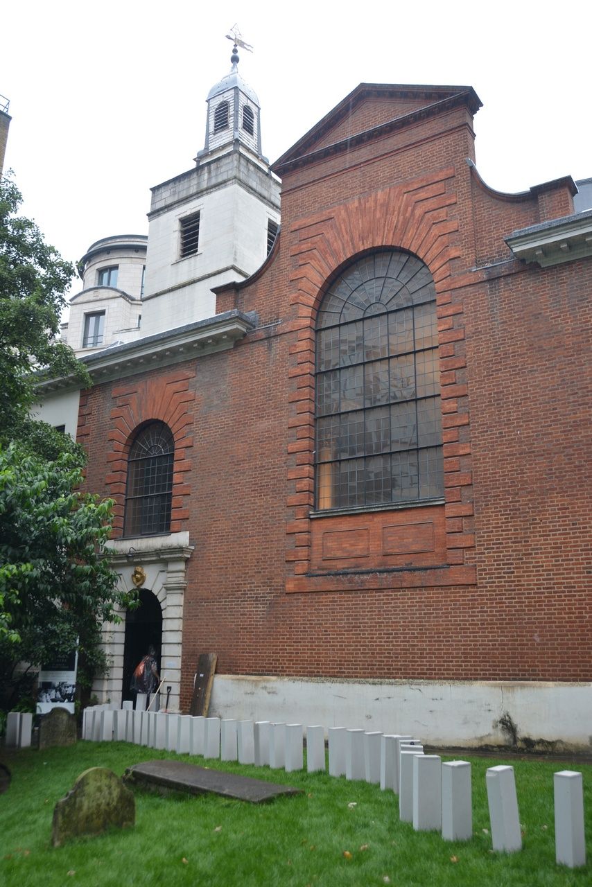 White blocks arranged on grass beside the brick exterior of a church.