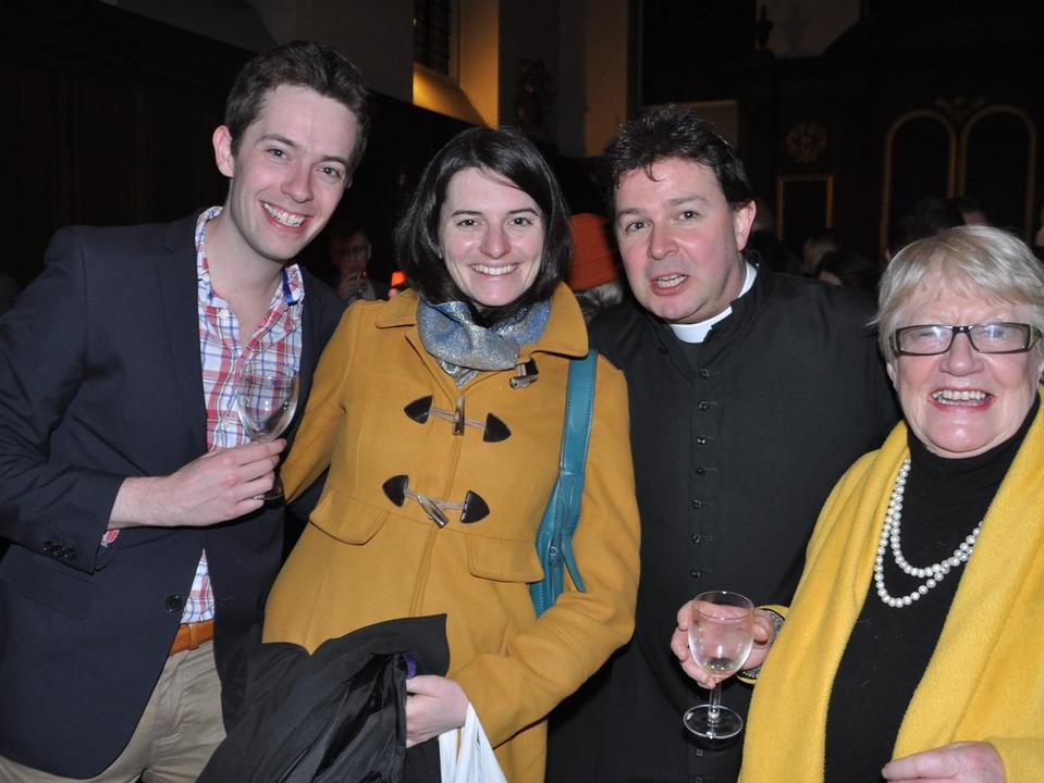Four guests smiling together at a church reception.
