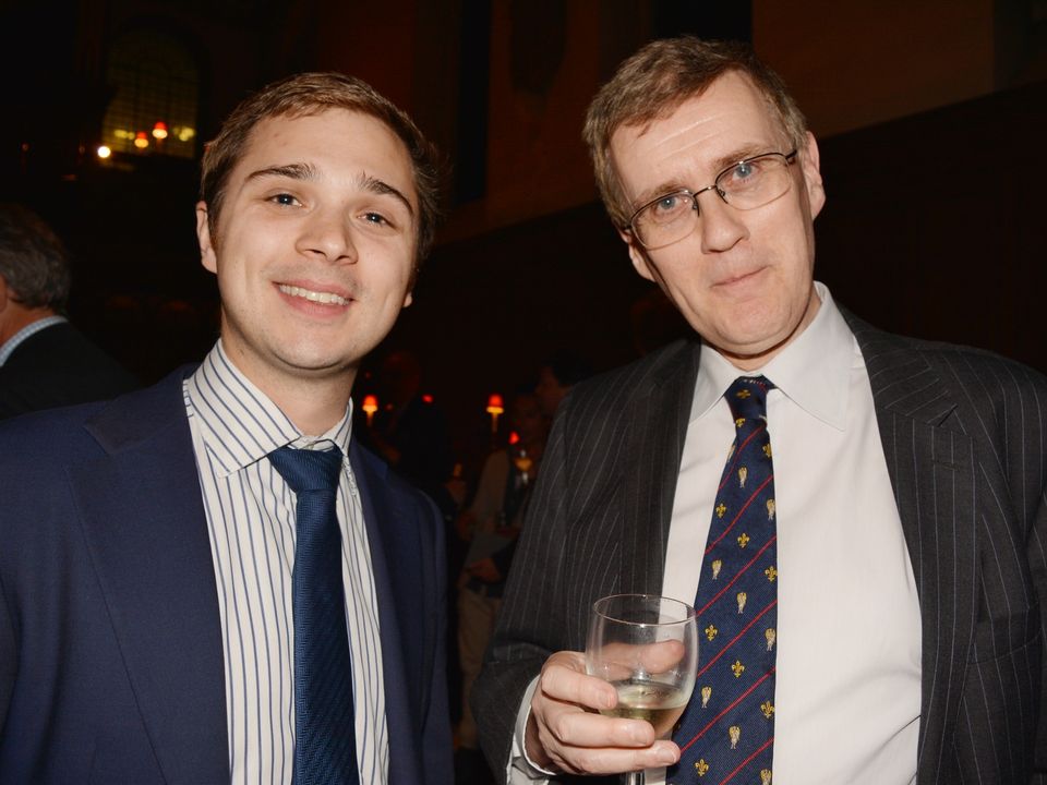Two guests in suits posing together at a church reception.