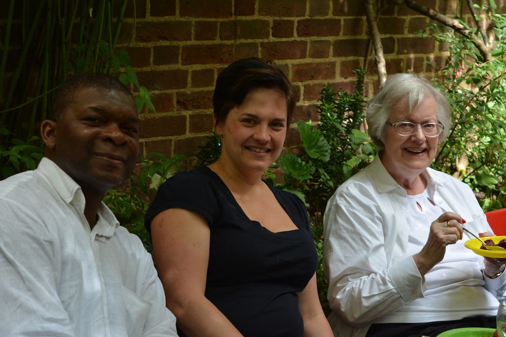 Three guests seated with food and drinks beside the courtyard wall.