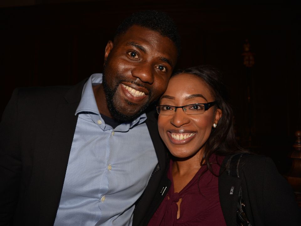 Two smiling guests standing together at an indoor reception.