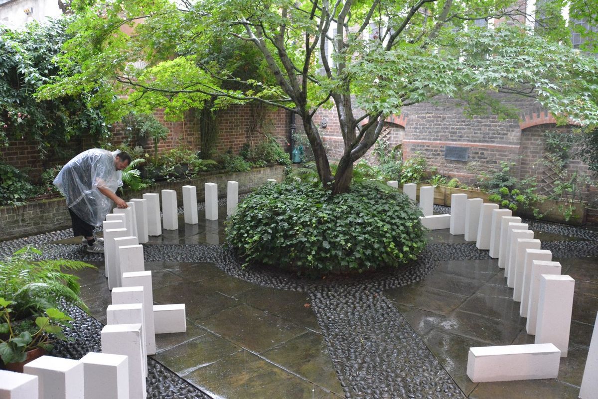 A wide view of white rectangular blocks surrounding the courtyard planting.