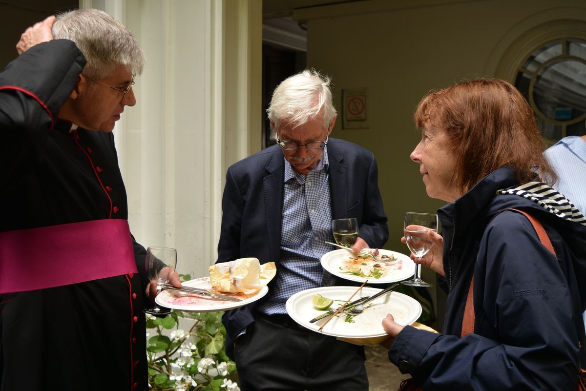Parishioners eating and talking together in the courtyard.
