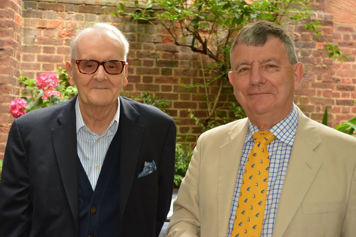 Two guests in jackets and ties standing together in the courtyard.