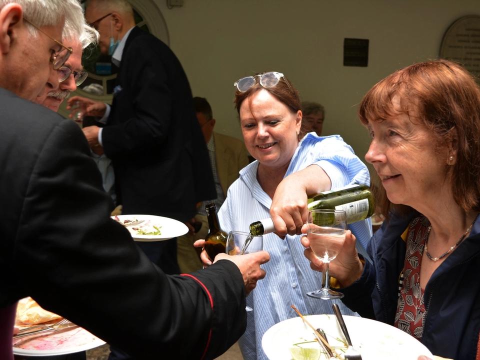 Guests sharing food and pouring drinks at a parish gathering.