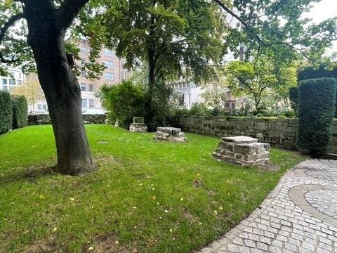 A paved path through a leafy garden with stone memorials.