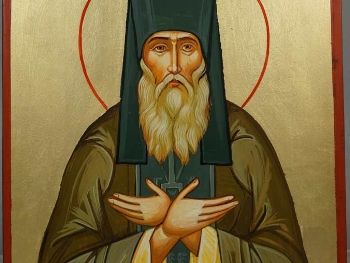 An icon of Saint Silouan in a dark hood, with one hand on his chest.