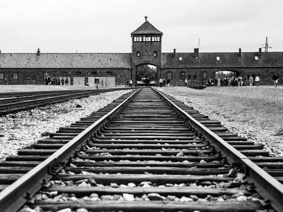 Railway tracks leading to a brick gatehouse in a black-and-white photograph.
