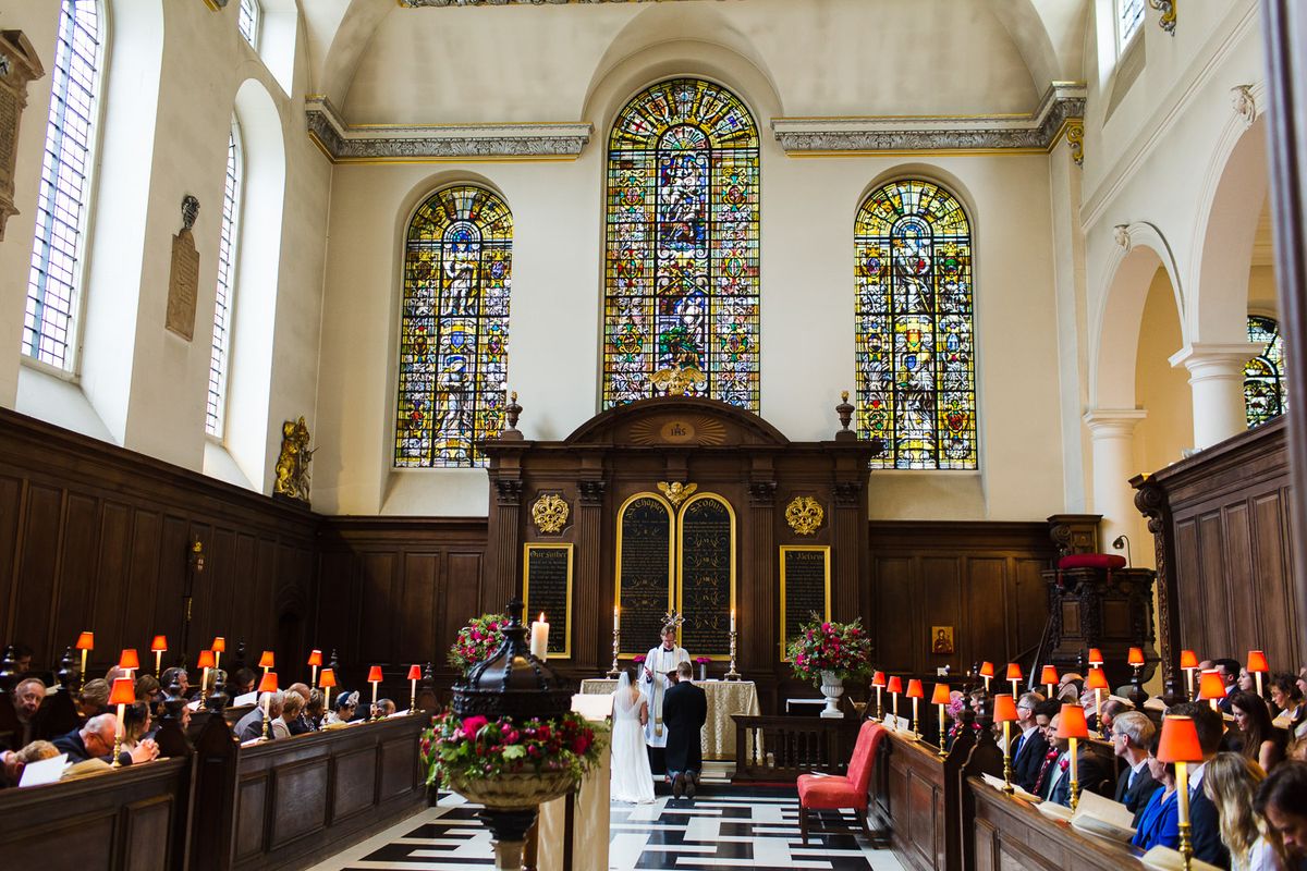 A wedding couple walking along the patterned aisle beneath stained glass.