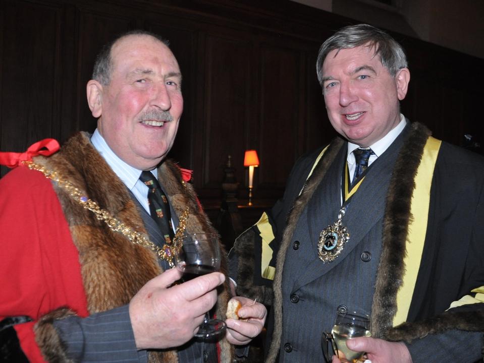 Two guests wearing ceremonial robes and chains at a reception.