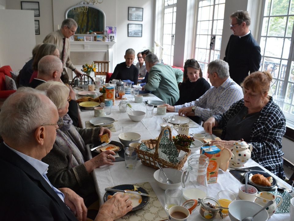 A wide view of guests sharing breakfast in a bright room.