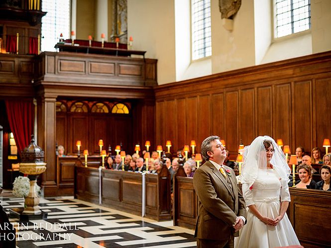 A bride accompanied down the aisle past the seated congregation.