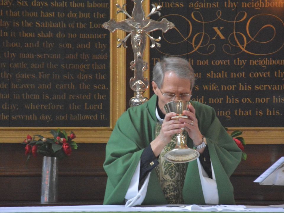 A priest holding a chalice at the altar.