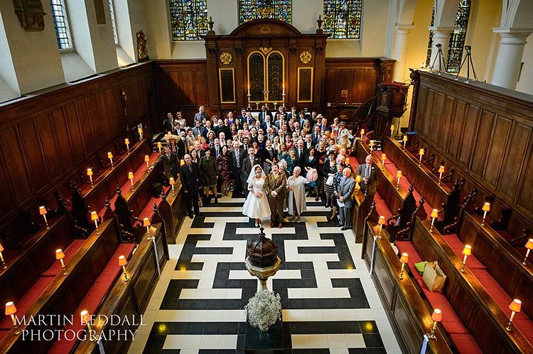 Wedding guests gathered around a couple in the church's central aisle.