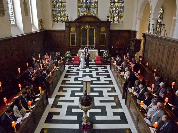 A wedding congregation seated on either side of the church's patterned aisle.