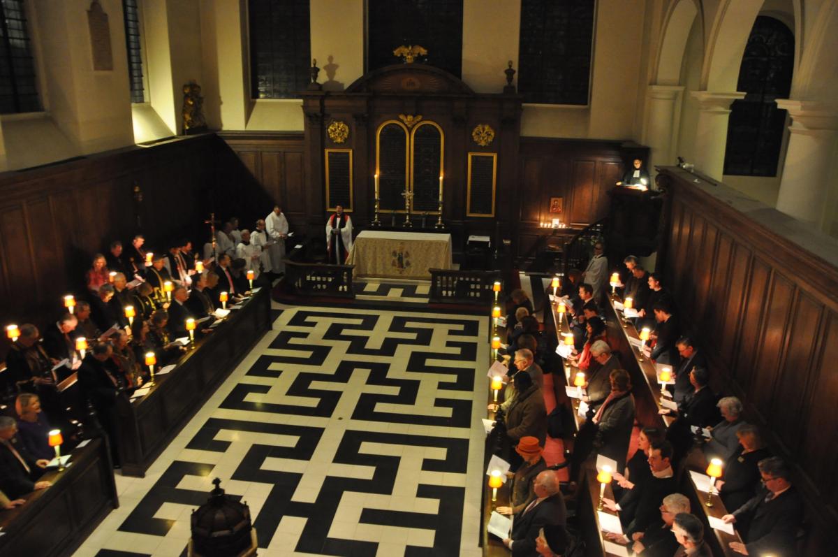 The church congregation gathered by lamplight around the patterned aisle.
