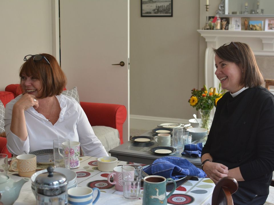 Two women seated with cups at the breakfast table.