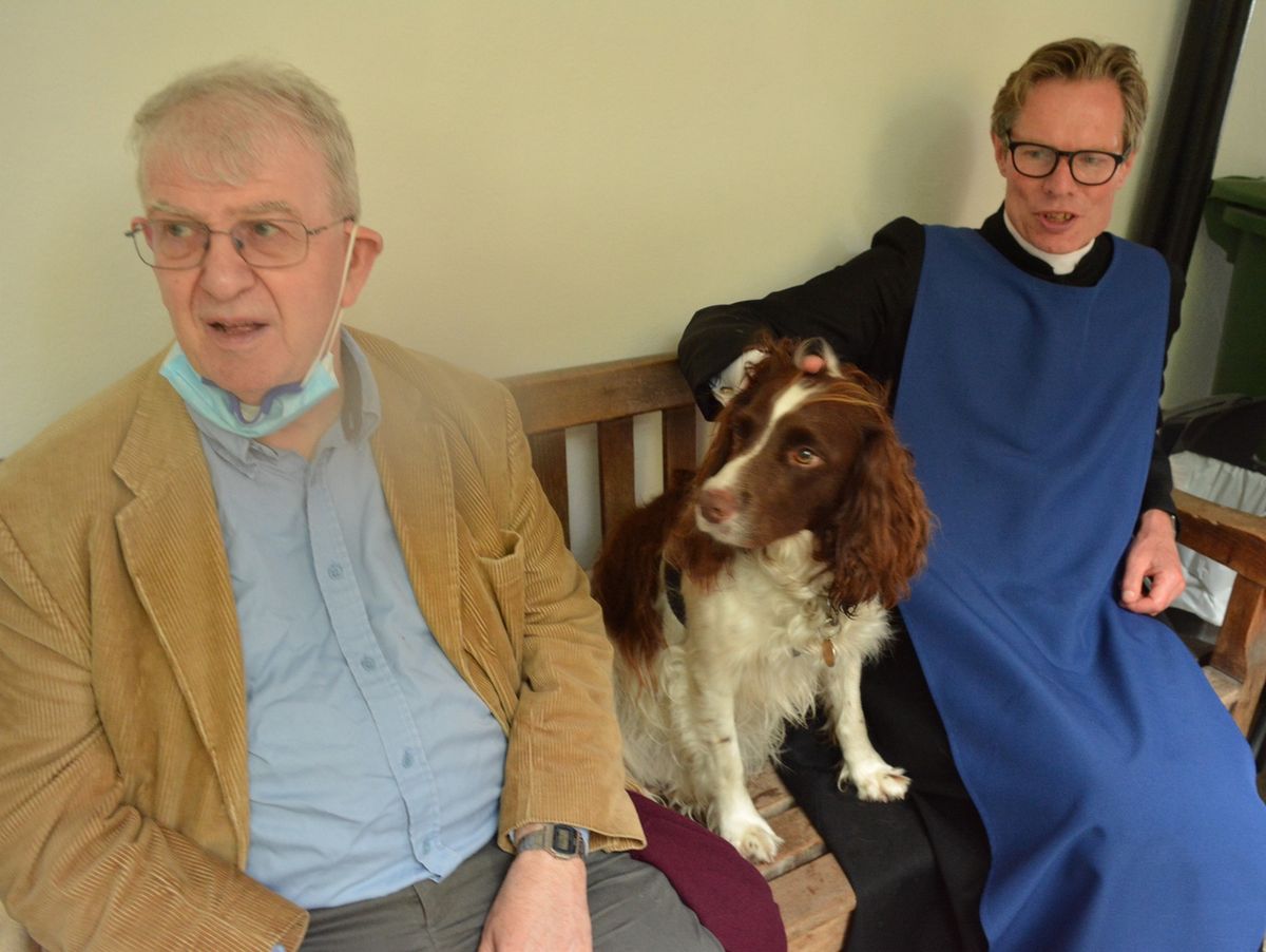 Two seated guests with a dog between them.