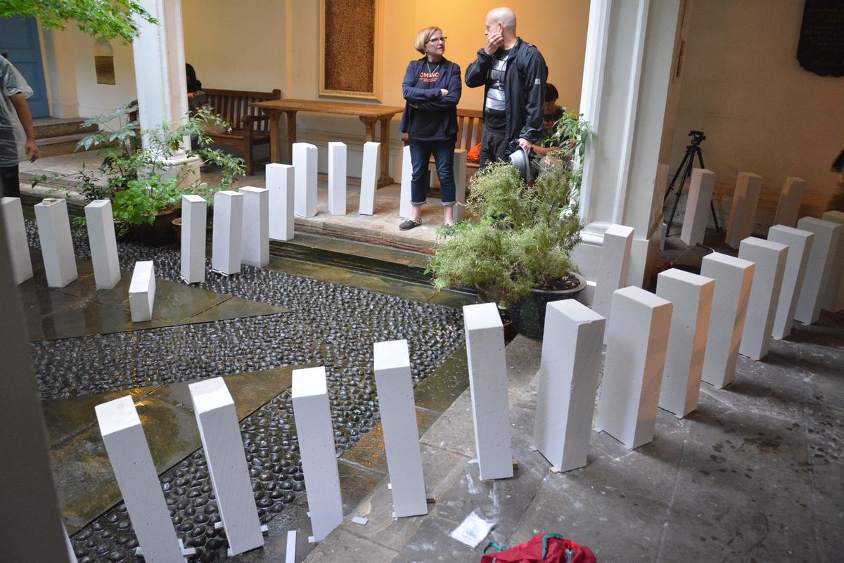 Visitors looking at upright white blocks arranged across the courtyard steps.