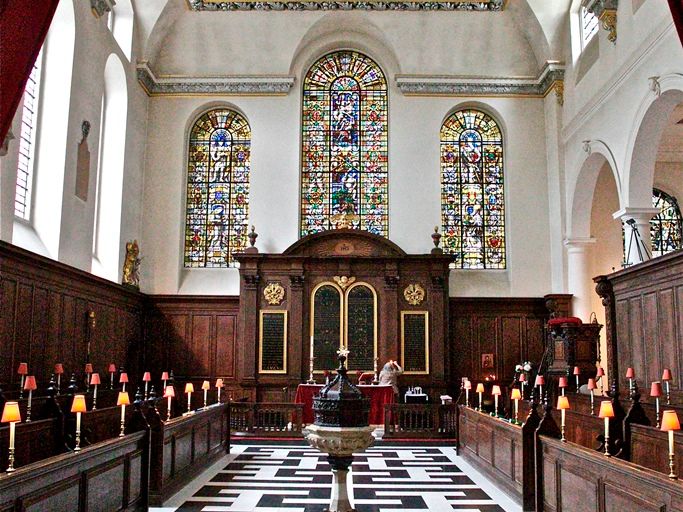 St Vedast's patterned central aisle leading towards the altar and stained-glass windows.