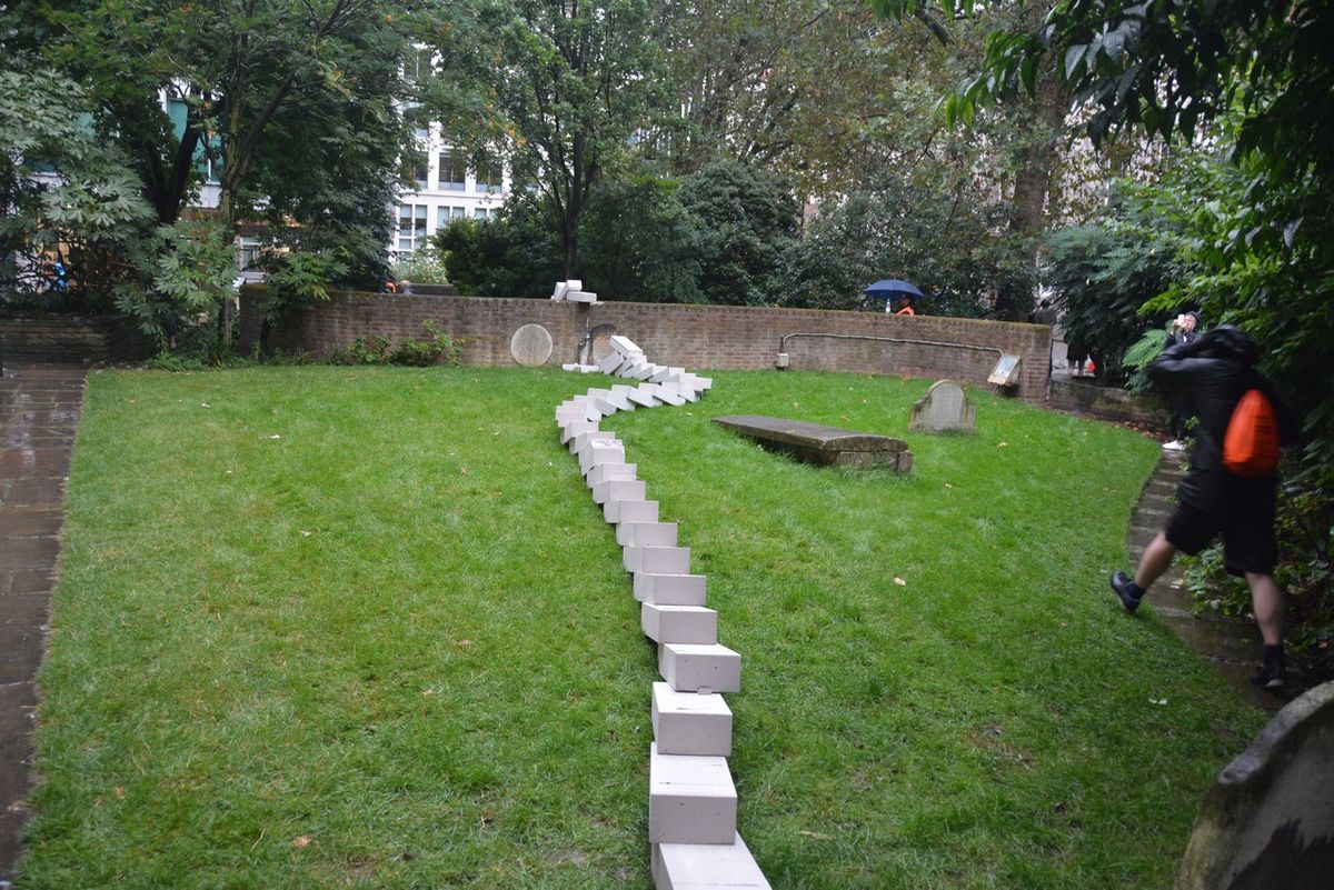 A winding line of fallen white blocks across a lawn.