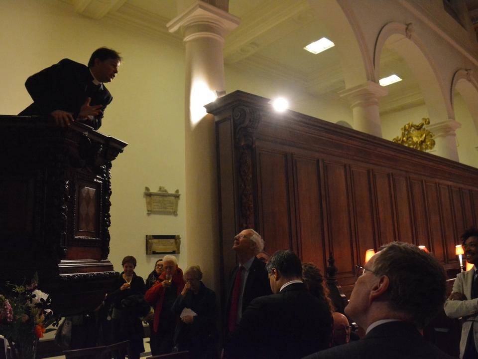 A speaker leaning over the pulpit towards the seated audience.