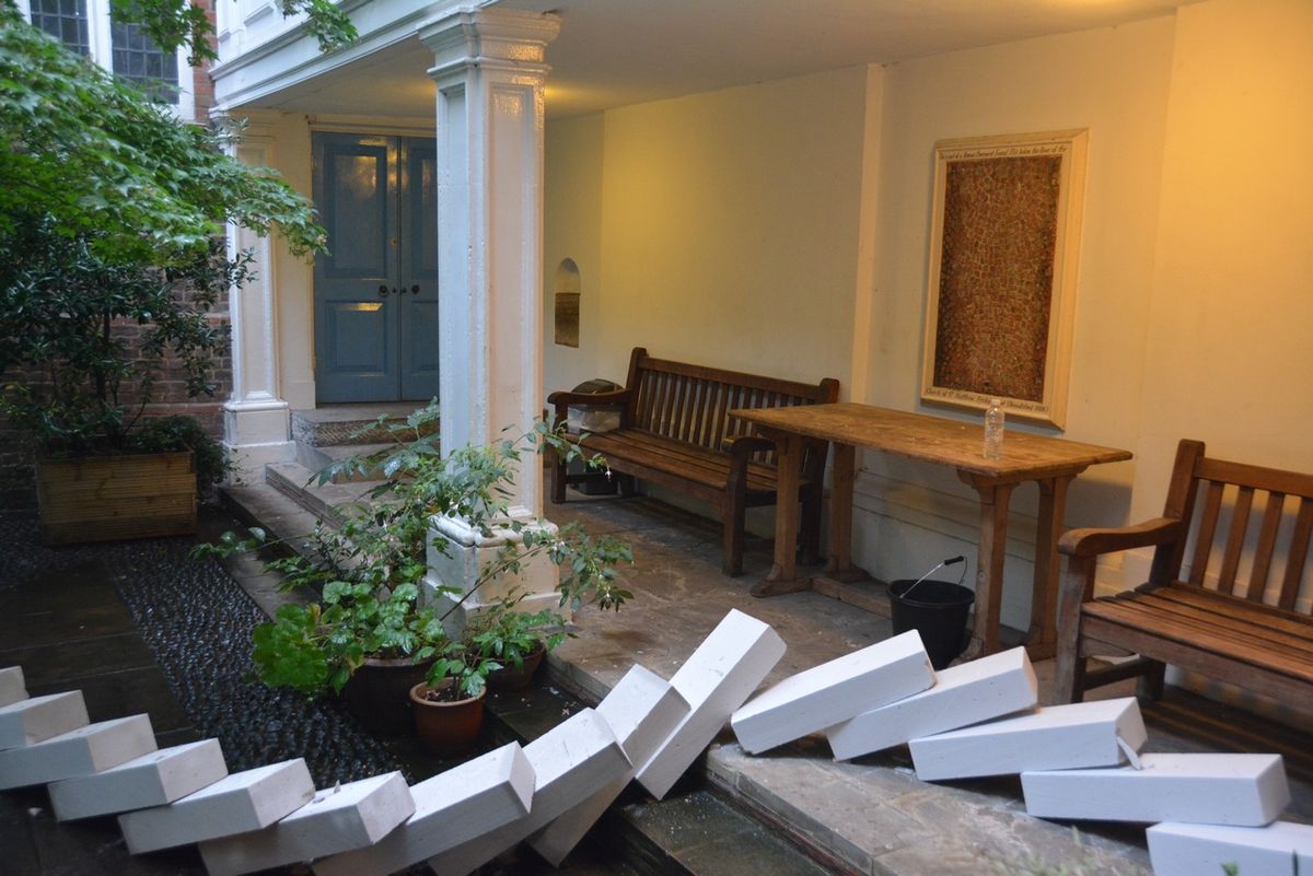 Fallen white blocks scattered across the courtyard beside wooden benches.