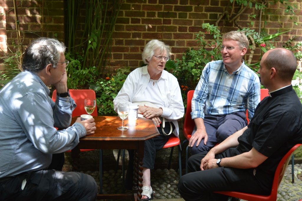 Four guests chatting around a courtyard table.