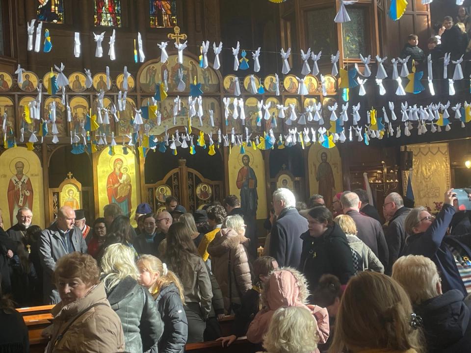 People gathered inside a church decorated with blue-and-yellow ribbons.