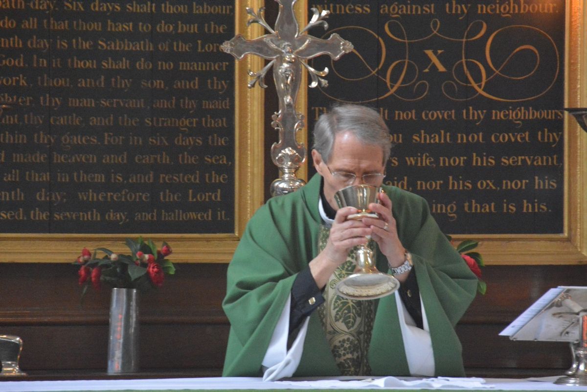 A priest holding a chalice at the altar.