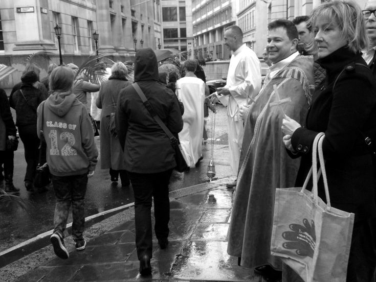 Donkey handlers and clergy gathered together beside a city street.