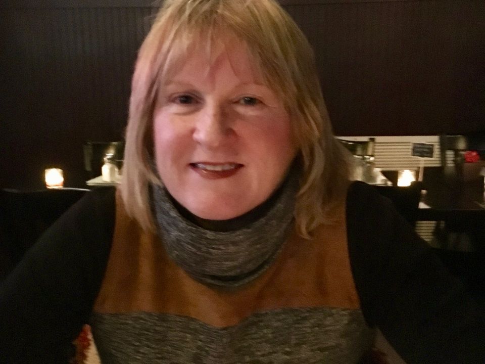 A smiling portrait of Joanna Sorohan seated indoors.