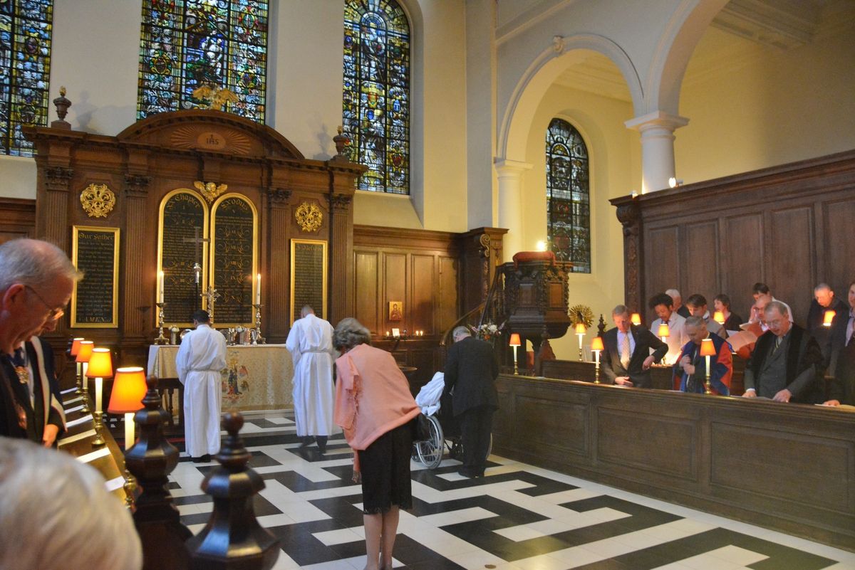 Worshippers and clergy gathered near the altar and stained-glass windows.
