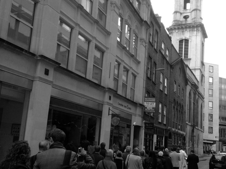 A church procession moving along the street towards St Vedast's tower.