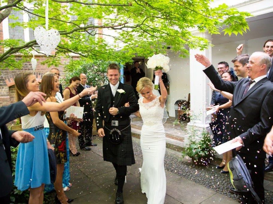 Guests throwing confetti over a wedding couple in the courtyard.