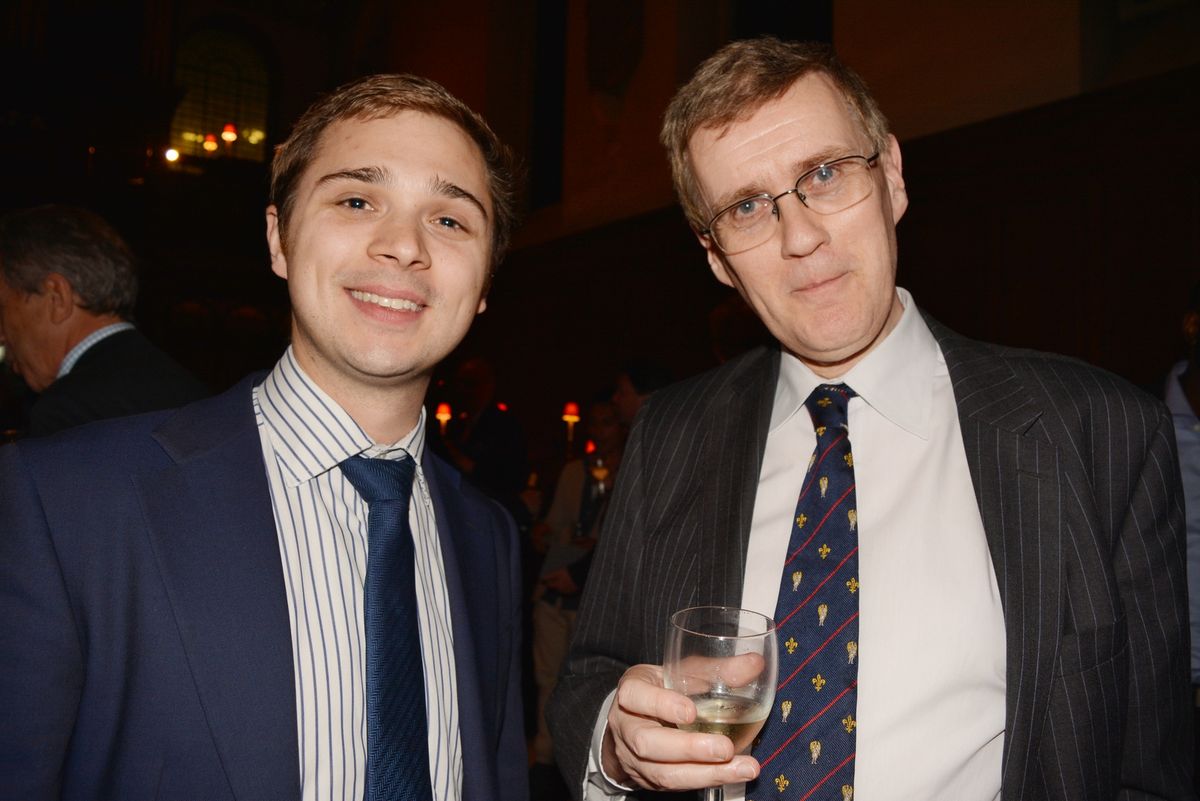 Two guests in suits posing together at a church reception.