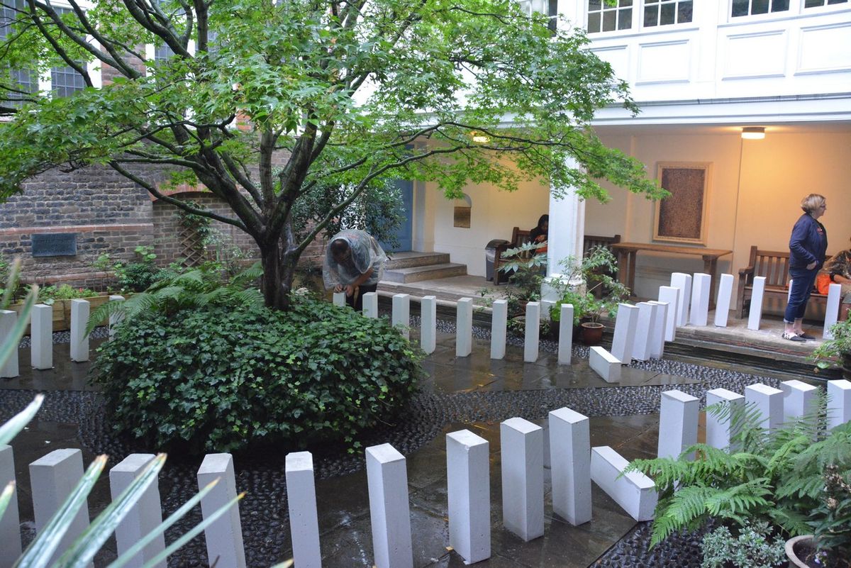 White blocks arranged around the tree and planted beds in the courtyard.