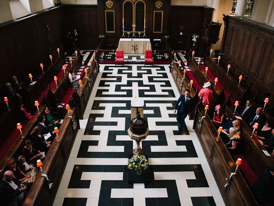 A wedding service viewed from above along the patterned church aisle.