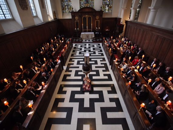 A wedding congregation viewed from the gallery above the patterned aisle.
